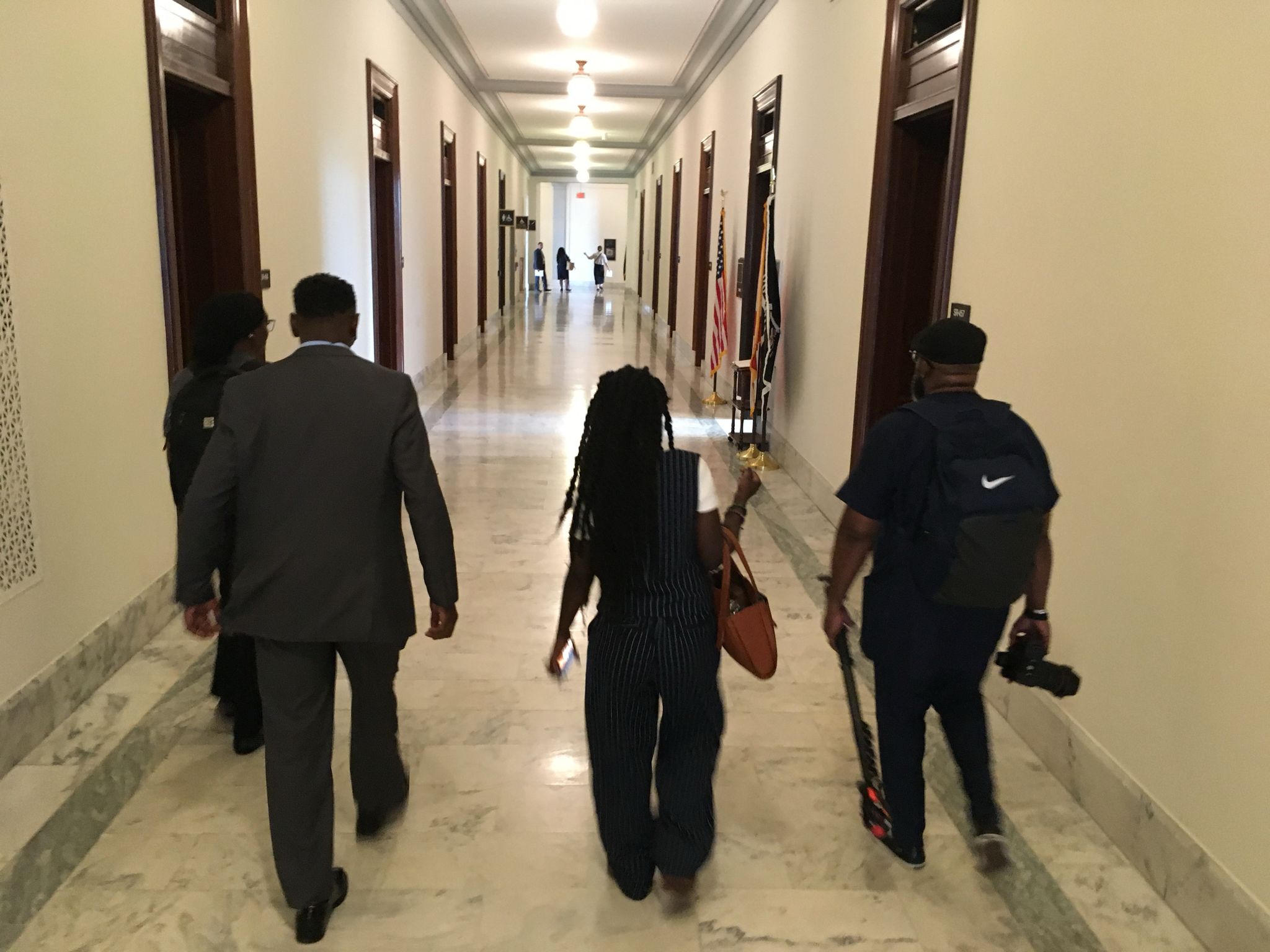 Three people walk down a long hall in the Russell Senate Office Building on Capitol Hill in Washington, DC